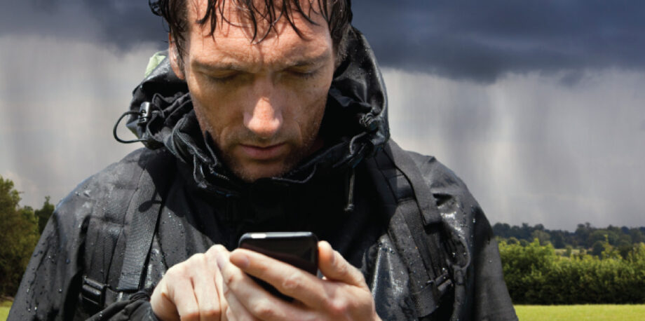 Rain soaked hiker using smartphone