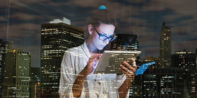 Young woman using digital tablet against city lights