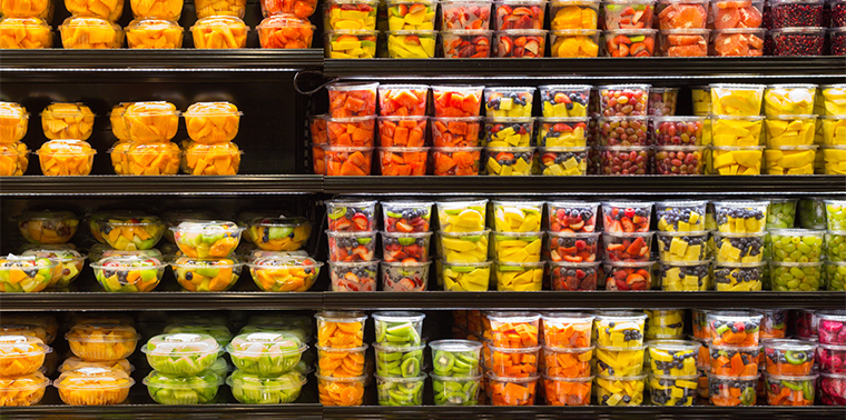 Assortment of cut fruit in plastic containers on display for sale at the supermarket