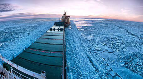 Icebreaker towing cargo ship through thick ice-field in Finland.