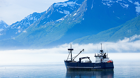 Large fishing boat anchored in Valdez, Alaska bay. Chugach Mountains in background.