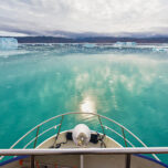 Panoramic view over boat bow towards the tranquil turquoise artic waters at the Eqi Sermia Glacier and Greenland Coast. Eqi Glacier, Ilulisaat, North West Greenland.