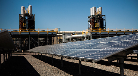 Solar panels in front of a natural gas power plant
