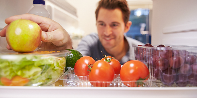 Man looking at produce in refrigerator