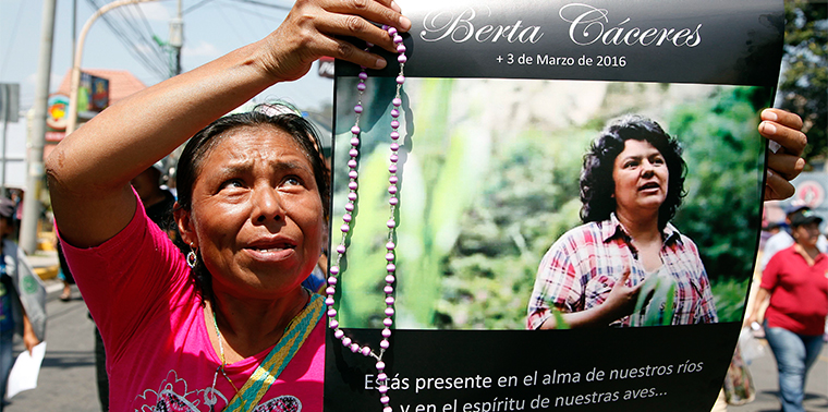 Woman holds up a poster with a photo of slain environmental leader Berta Caceres