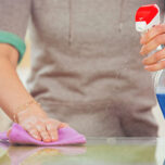 Woman cleaning glass table with spray