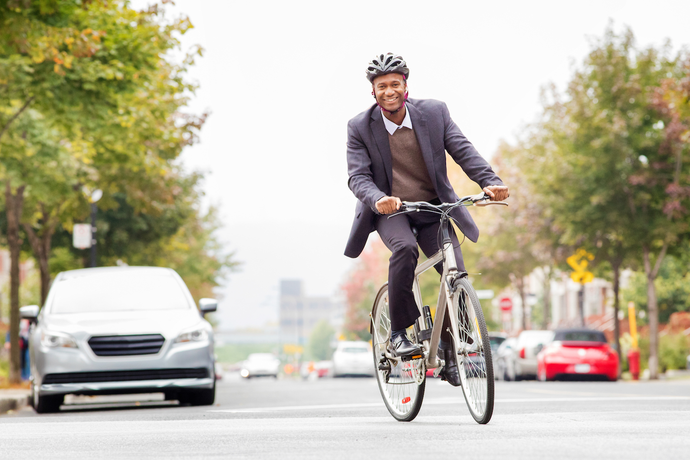 Single black male in his 30s smiling while commuting to work by bicycle