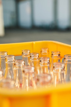 Photo of clear glass bottles in yellow bin