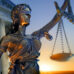 A statue of the blindfolded lady justice in front of the United States Supreme Court building as the sun rises in the distance symbolizing the dawning of a new era.