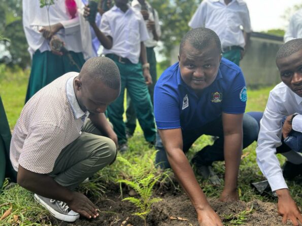 Photo of man named Juma Salum planting a plant with other people around him.