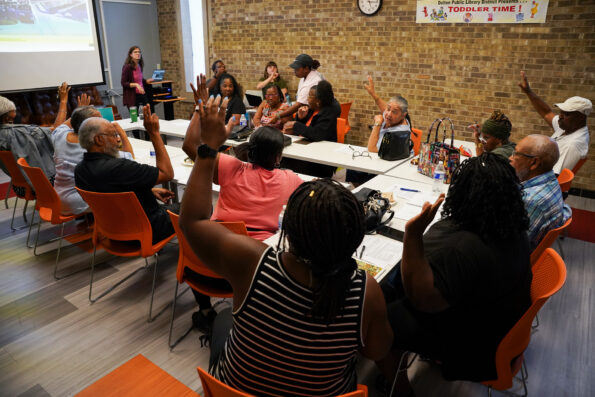 Fourteen Dolton residents, sitting in orange chairs around conference tables, raise their hands to vote on various flood mitigation projects