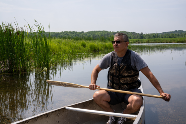 Image shows Todd Moilanen, cultural resources director for the Mille Lacs Band of Objibwe, canoeing on Ogechie Lake in Kathio Township, Minnesota