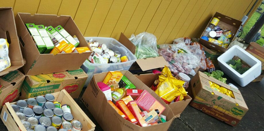 Food with no expiration dates but only just past the 'best by' dates by a couple months scheduled to go to the trash saved and given to those in need. Image shows boxes of packaged and fresh food in large boxes next to a yellow wall.