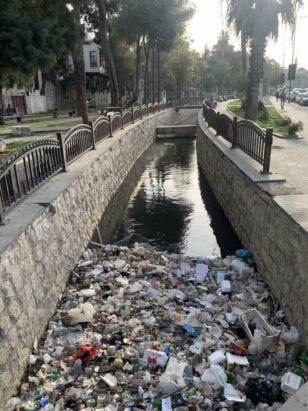 Image shows large pile of trash clogging the Barada River in Damascus, Syria.