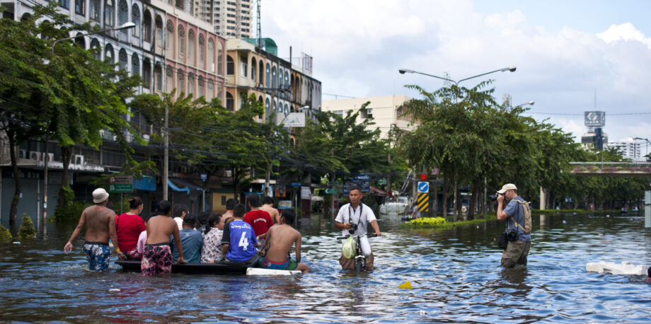 foreign journalist take photographs of people evacuating from the vast of flooding on the public road near Chao Phraya River